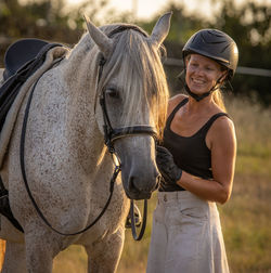 Lusitano mare, female dressage rider, saddle and bridle, helmet, on grass.