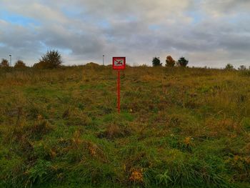 Sign board on field against sky