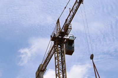 Low angle view of crane at construction site against sky