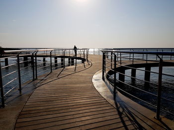 Pier over sea against clear sky during sunset