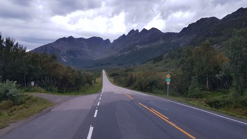 Road leading towards mountains against sky