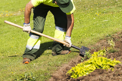 Unrecognizable gardener working with hand tools in municipal garden