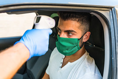 Doctor wearing a face mask to use infrared forehead thermometer