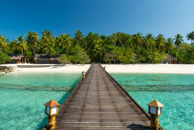 Pier over lake against clear blue sky