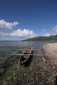 Boat moored on beach against sky