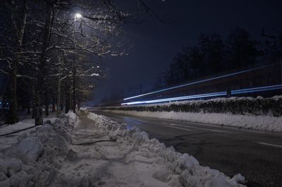 Road amidst trees during winter at night