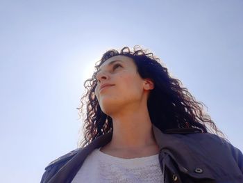 Portrait of young woman standing against clear sky