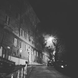 Illuminated street amidst buildings in city at night