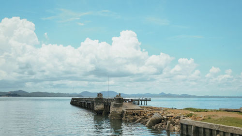 Pier on sea against cloudy sky