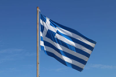 Low angle view of flag against blue sky