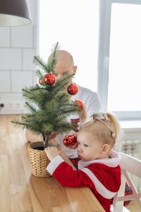 Cute girl playing with christmas tree at home