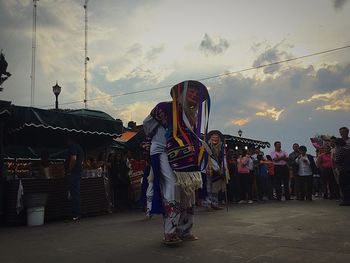 Group of people at amusement park against sky during sunset