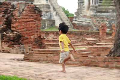 Full length rear view of girl walking on historic building