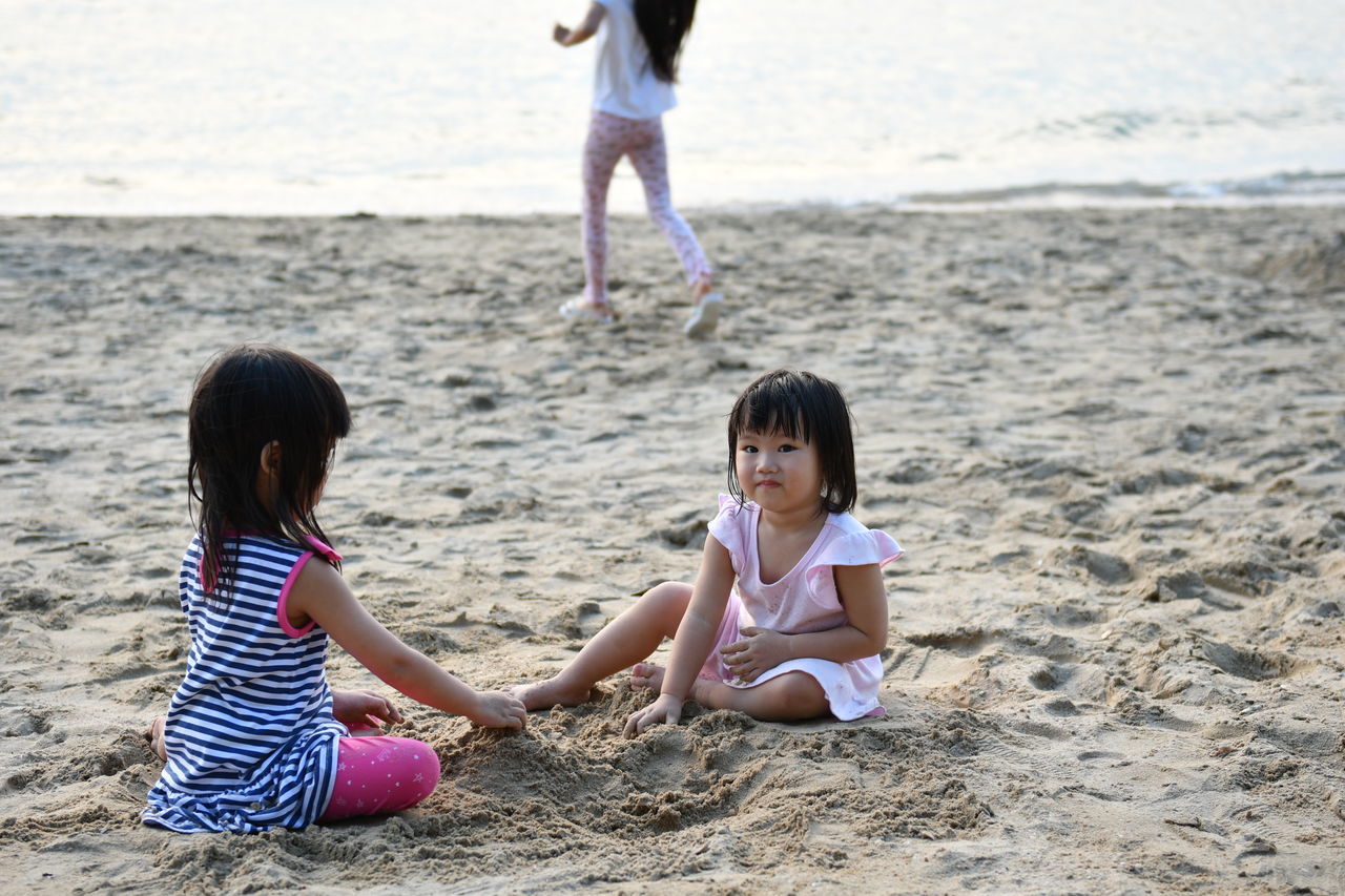 SIBLINGS SITTING ON BEACH