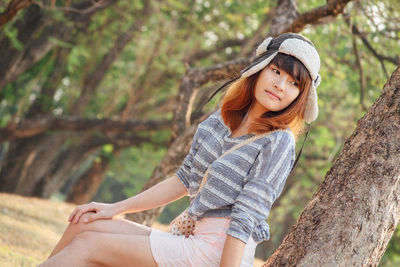 Midsection of woman sitting on tree trunk