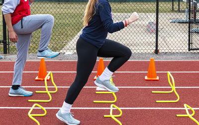 Low section of woman running over hurdles at sports track