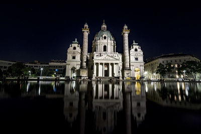 Karlskirche by pond against sky at night