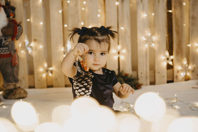 A baby girl with pigtails shows a christmas pineapple