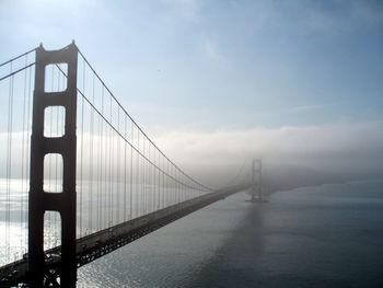 Golden gate bridge over bay against sky during foggy weather