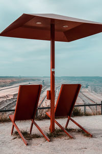 Deck chairs on beach against sky