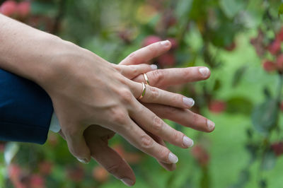 Close-up of couple holding hands against plants