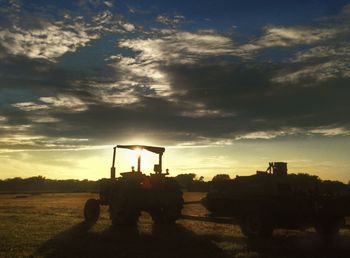 Tractor on field against dramatic sky