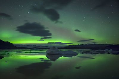 Scenic view of aurora borealis over lake against sky at night