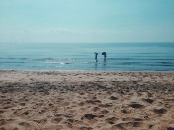 Two people walking in calm sea