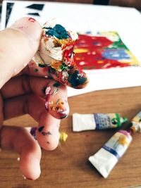 Cropped hand with colorful watercolor paints over table