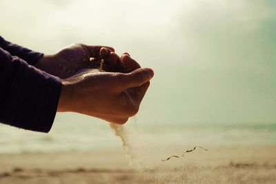 Cropped hand of person holding sand at beach