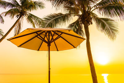 Palm trees on beach against sky during sunset