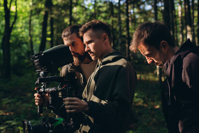 Young man photographing in forest