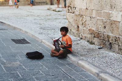 Full length of boy playing on cobblestone