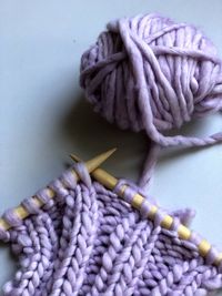 Lilac knitting project on wood needles. white background.