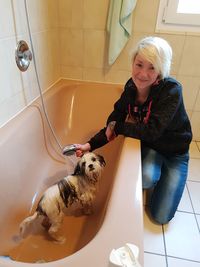 Young woman with dog in bathroom