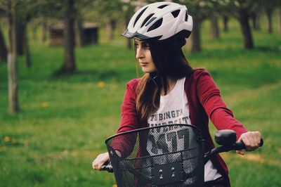 Young woman with bicycle standing on grass