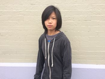 Portrait of teenage girl standing against wall