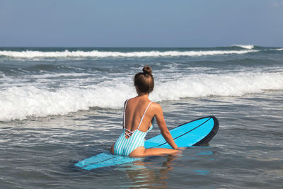 Rear view of woman swimming in sea against sky