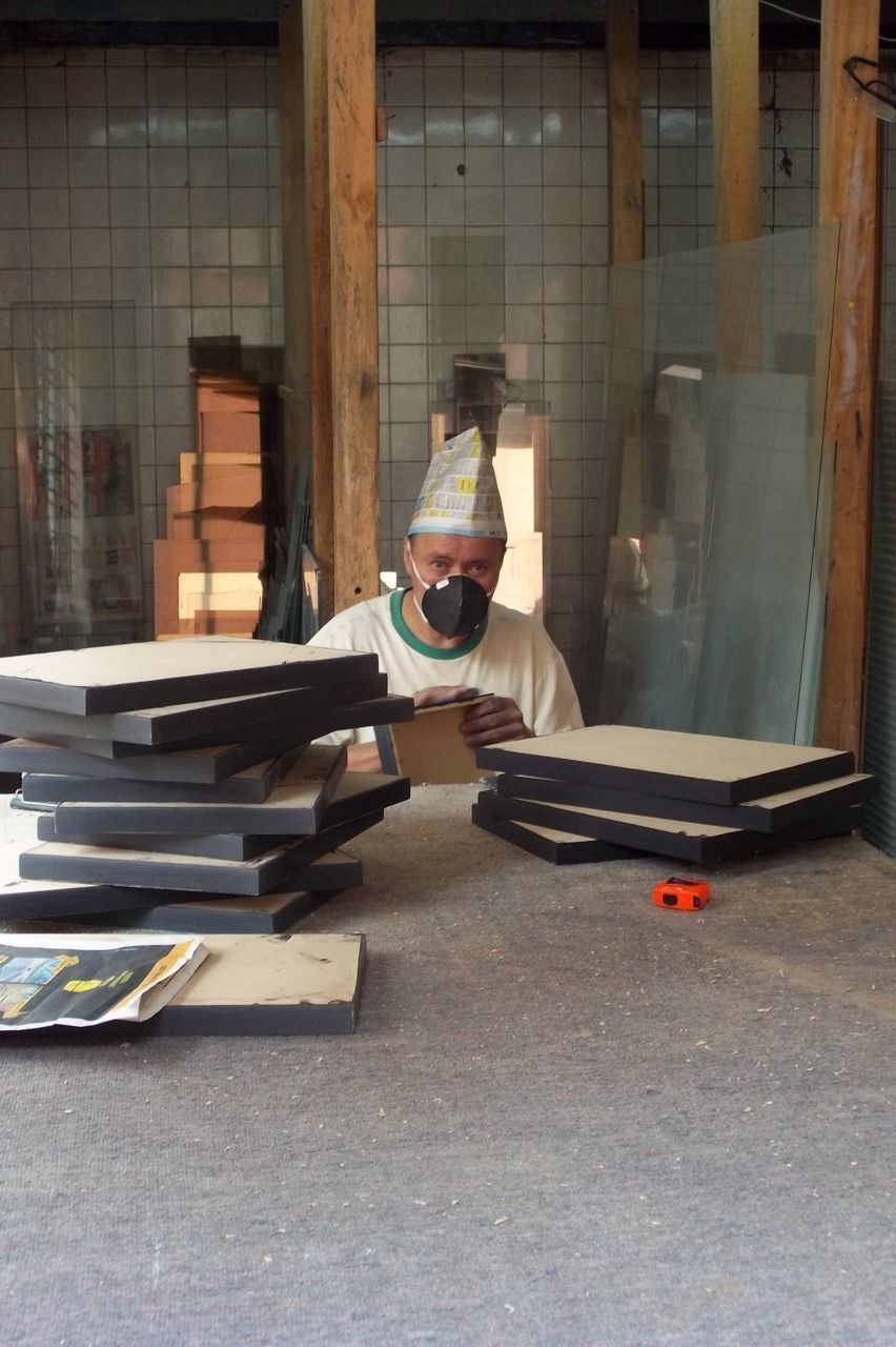 MAN SITTING ON TABLE BY STACK OF BOOKS ON SHELF