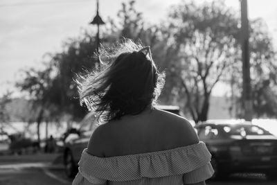Rear view of woman standing against car