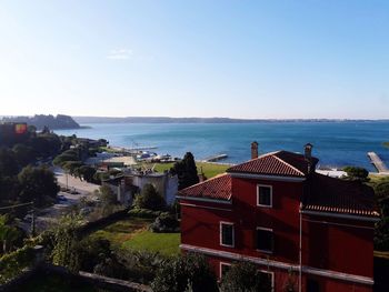 Houses by sea against clear sky