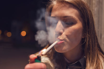 Close-up portrait of young woman smoking outdoors