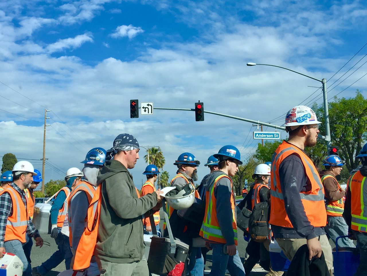 group of people, real people, men, sky, occupation, cloud - sky, nature, transportation, day, helmet, clothing, people, rear view, headwear, reflective clothing, safety, hat, standing, protection, medium group of people, outdoors, uniform