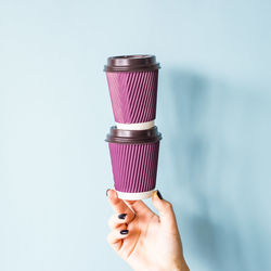 Close-up of hand holding ice cream against white background