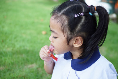 Cute girl licking chocolate on plastic outdoors