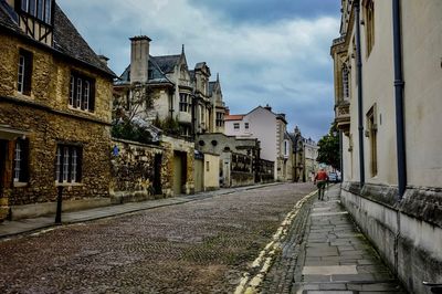 Man walking on street amidst buildings in city