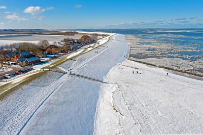 Aerial from the snowy village moddergat at the frozen waddensea in winter in the netherlands