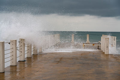 Sea waves splashing on shore against sky