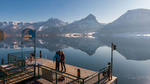Man looking at lake by mountain against sky