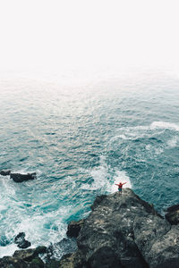 High angle view of woman on cliff by seascape against sky